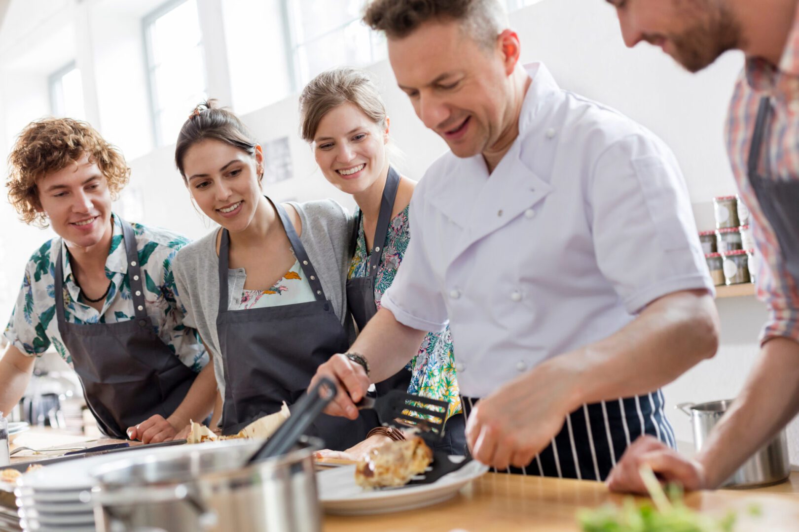 Students watching chef teacher in cooking class kitchen